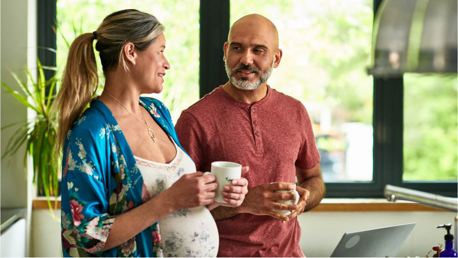 Pregnant woman and man talking while drinking coffee