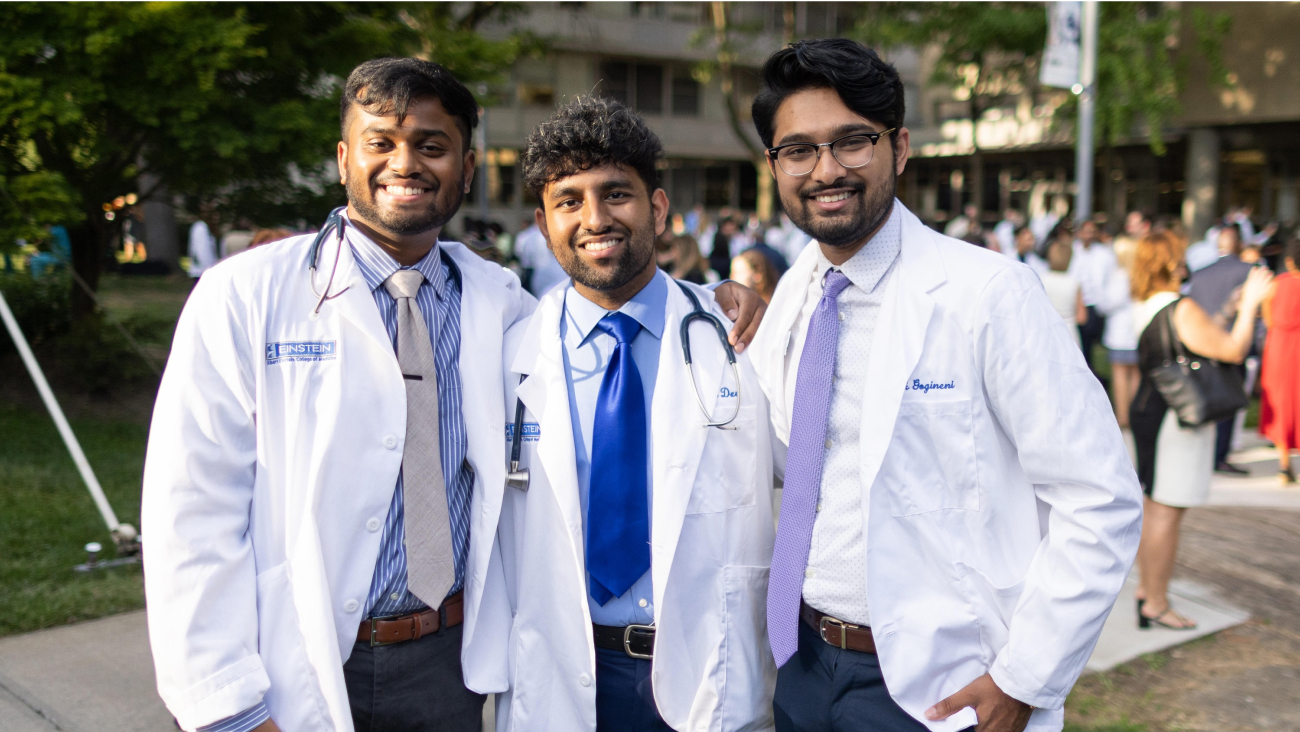 Three smiling med students in white coats. 