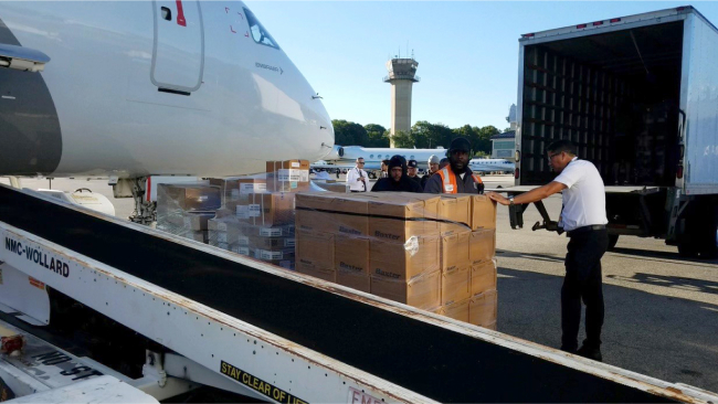 A team breaks down palleted supplies to be loaded onto the jet via conveyor belt.