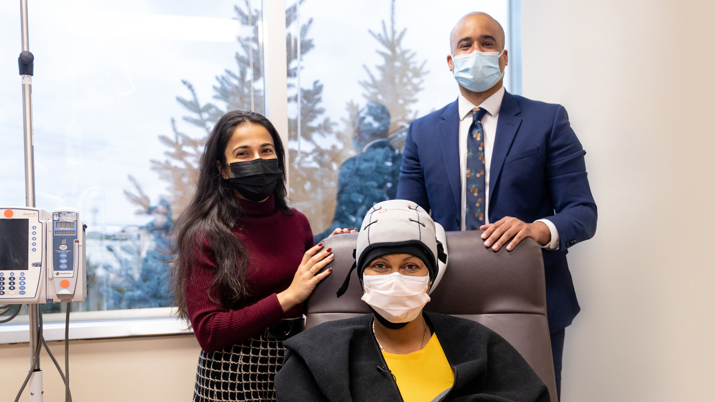 Doctor and woman standing with woman seating wearing hair loss treatment cap