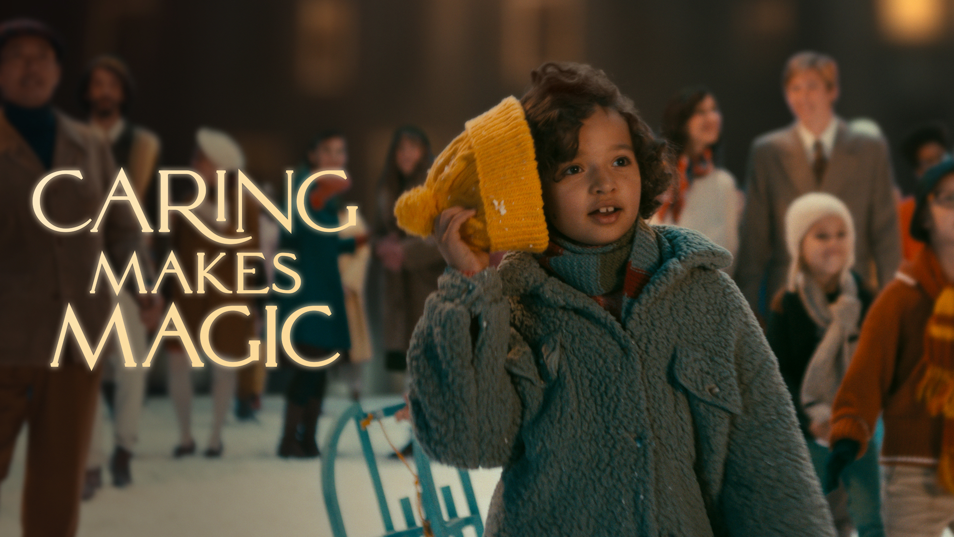 "Caring is Magic" in gently glowing golden letters, to the left of a  little girl, dressed for winter, pulling a knit cap from her head.  She looks on with wonder, along with other figures behind her. There is snow on the ground.