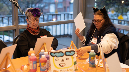 Two BOLD participants do a Halloween craft at a table. 