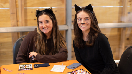 Two partiers dressed as cats smile at the camera.