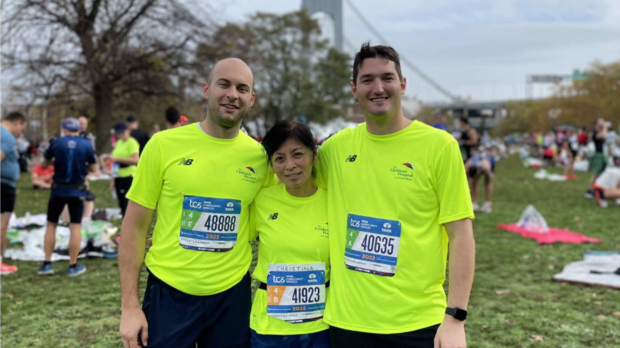 Three runners in neon yellow shirts pose and smile for the camera.