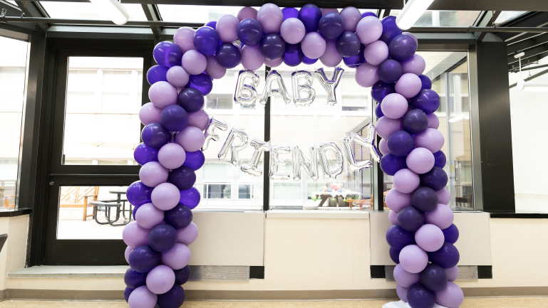 Purple and violet balloon arch with the words Baby Friendly suspended below it in silver inflated balloon letters.