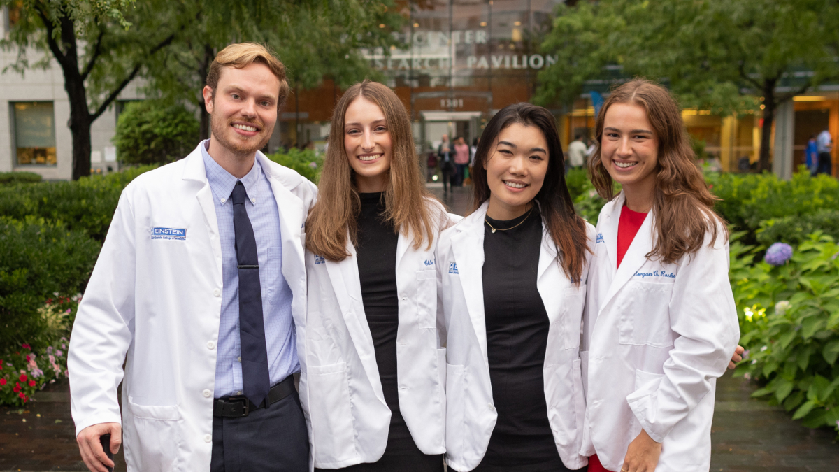 Four proud white coat recipients pose for a photo with big smiles.