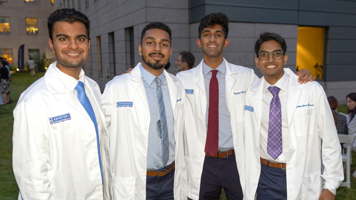 Four proud white coat recipients pose for a photo with big smiles.