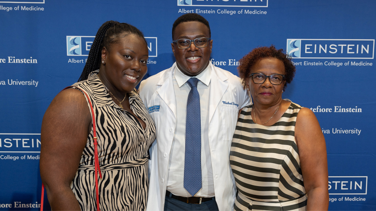A proud white coat recipient poses for a photo with family members.