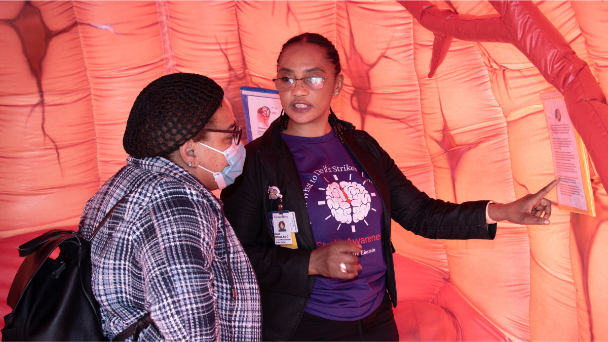 A volunteer and participant discuss stroke awareness inside the special event pavilion, an inflatable structure designed to look like a human brain.
