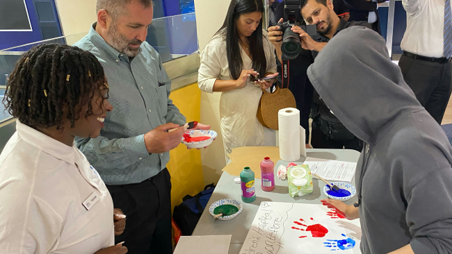 Kids and adults work with paint to create handprint pictures.