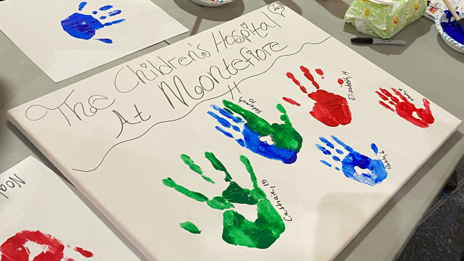 A canvas with five children's handprints.