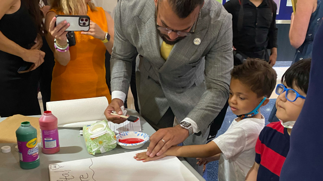 Adults and kids work with paint to create handprint images.