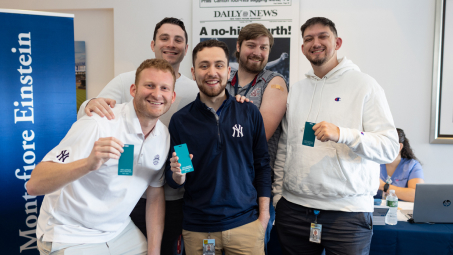 Five proud Yankees staffers hold up green flu-vaccine cards.