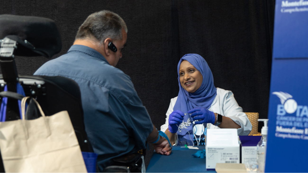 A staff member talks with a participant at a table.