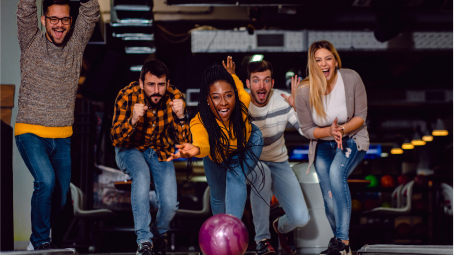 A group of young people bowling.  