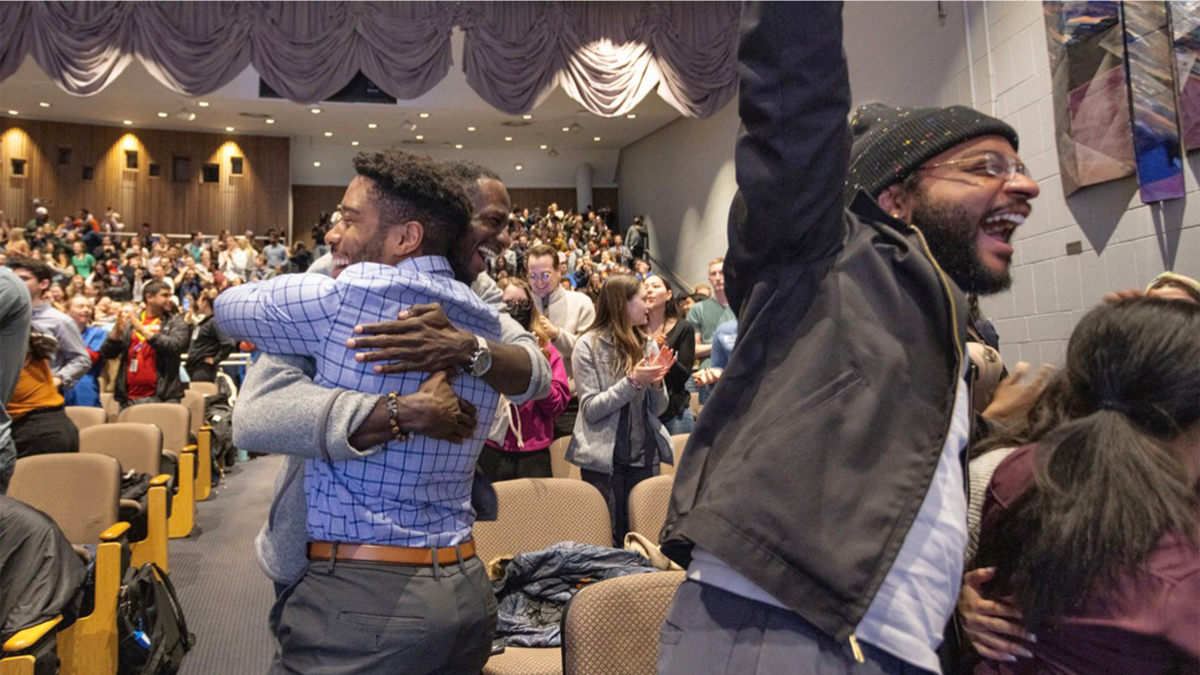 Students cheer and hug, reacting to the news.