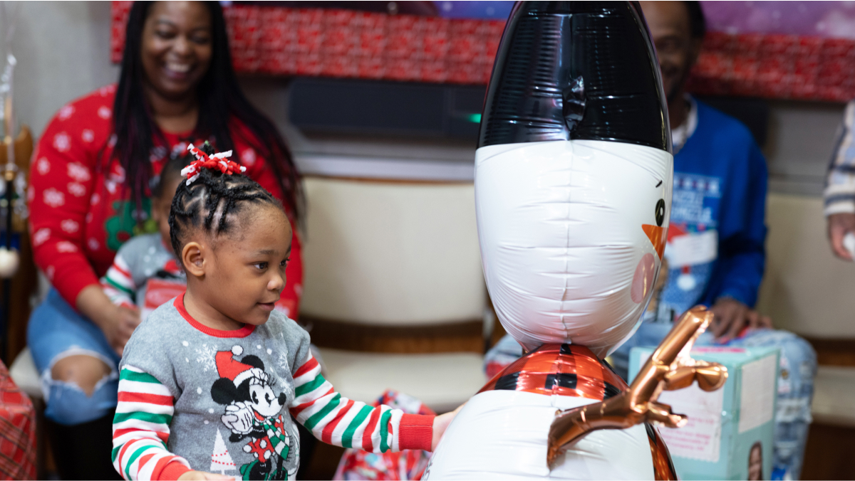 A young child looks at an inflated snowman decoration.