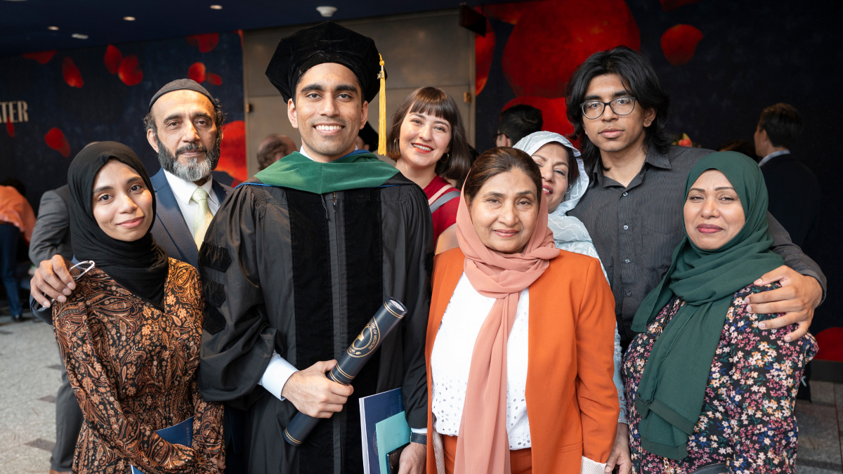 Proud friends and family pose all around a recent graduate.