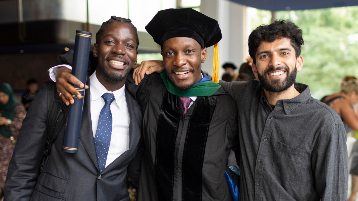 Proud friends and family pose with a smiling recent graduate.