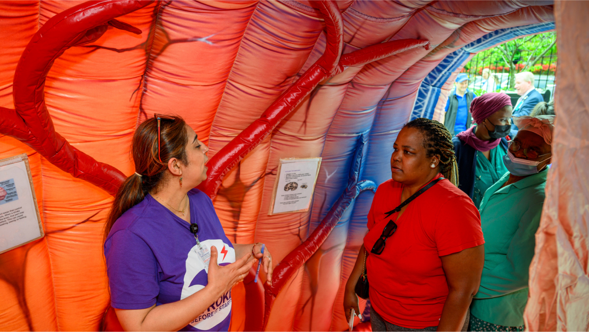 Participants walk through a large inflatable tunnel lined with informational posters.