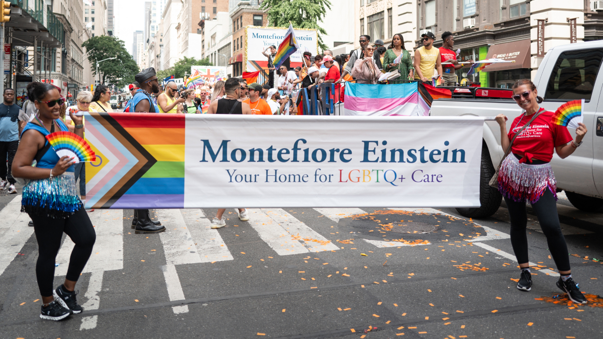 Montefiore Einstein parade goers carry the colorful banner on the parade route.