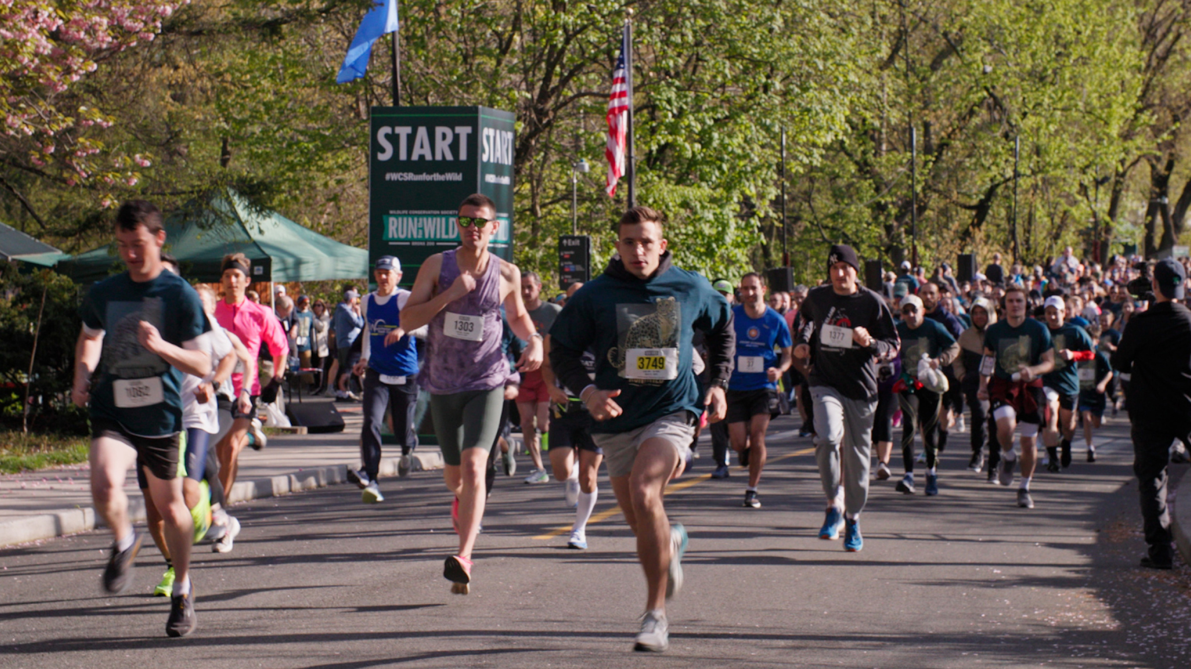 Runners take off from the starting line on a bright sunny day.