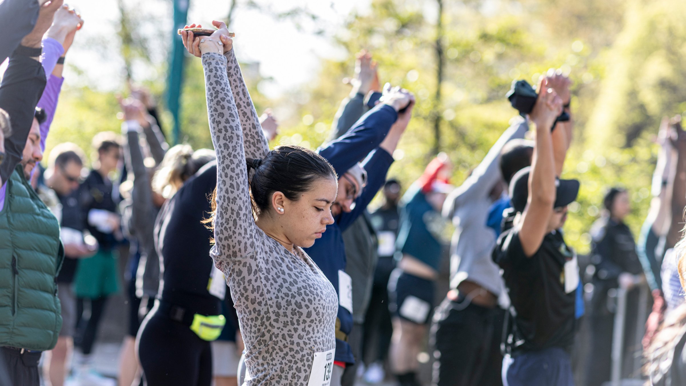 Runners stretch their arms on a bright, sunny day.