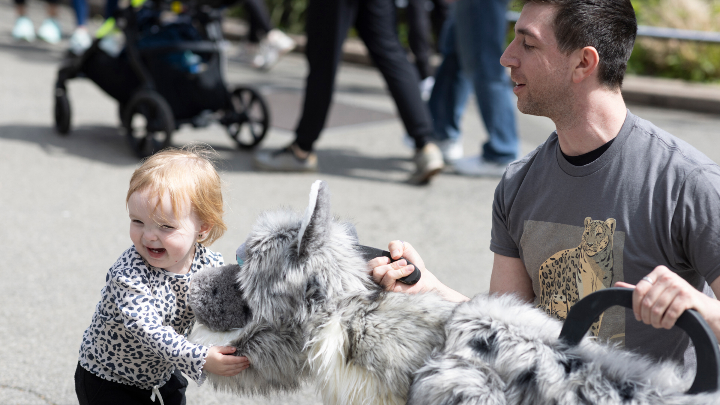 A toddler laughs and pets a large furry puppet.