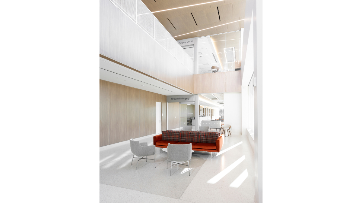 A waiting area featuring a bright, airy design with neutral tones, accented by a large wine colored couch as a focal point.