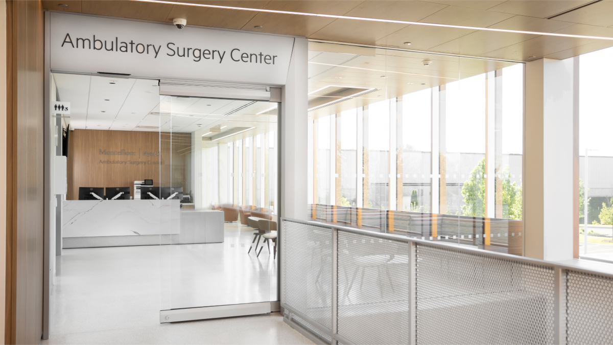 Bright natural light filters through floor to ceiling glass windows and a glass wall in the entryway.