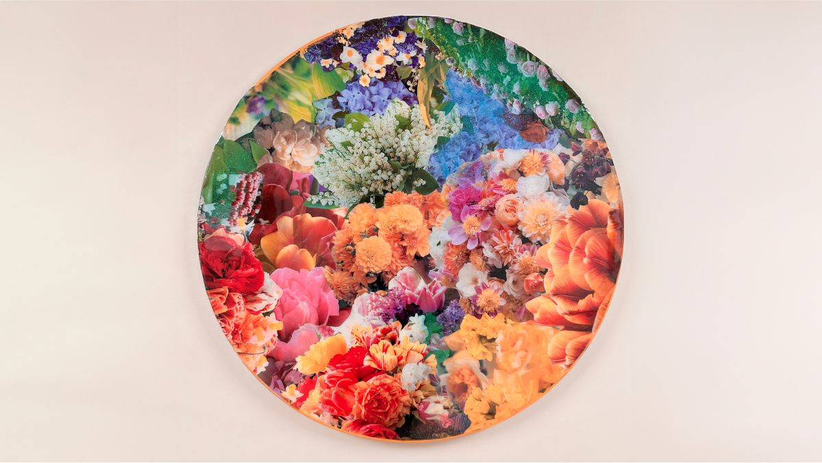 On a round canvas, an image of a wide array of flowers in warm tones below.  Above, blues and greens.