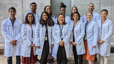 12 Doctors in new white coats smile at the camera. 