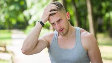 A young man holding his head, as if he has a headache.