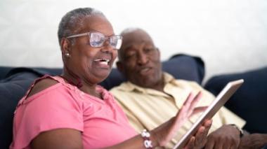 Two people relaxing on a couch using a tablet.