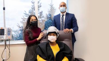 Doctor and woman standing with woman seating wearing hair loss treatment cap