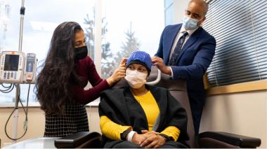 Doctor and woman standing with woman seating wearing hair loss treatment cap