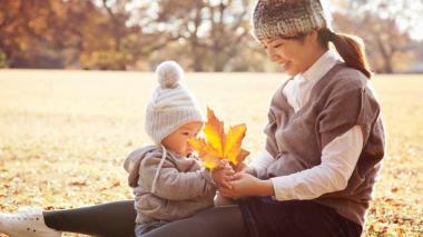 Mother and child at the park looking at a leaf