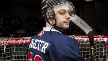 Jake dressed in hockey gear in front of a hockey goal.