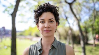 A young woman in a summer shirt looks toward the camera.