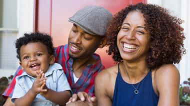 A happy family of three smiles toward the camera.