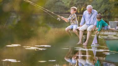 A man and two children fish from a dock.