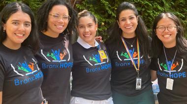 Five young women in matching T-shirts pose for a photo.